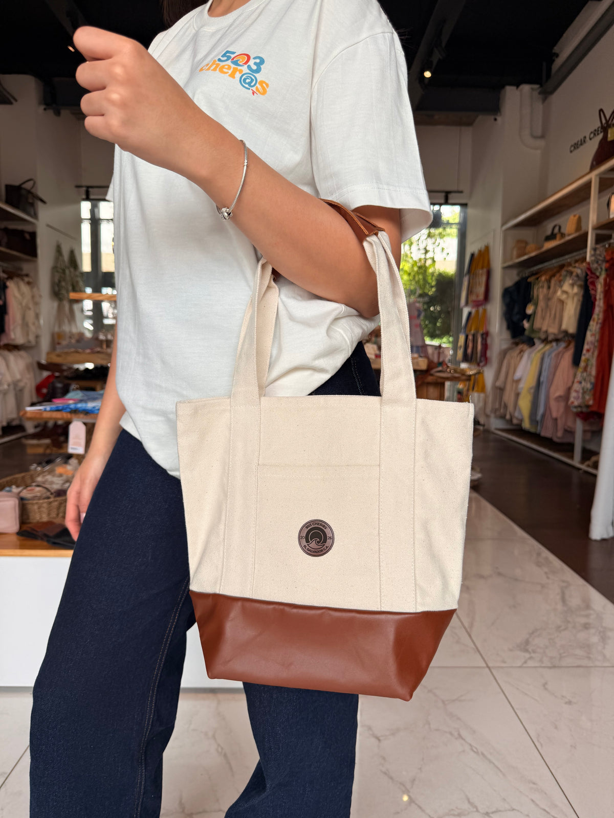 Woman carrying 503Cher@s Small Tote Bag in store, canvas body with leather base