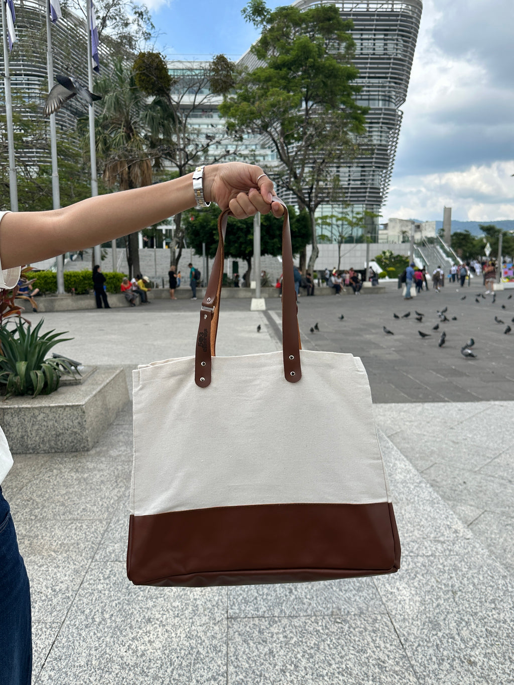 503Cher@s Medium Tote Bag held up in San Salvador plaza with city skyline in background