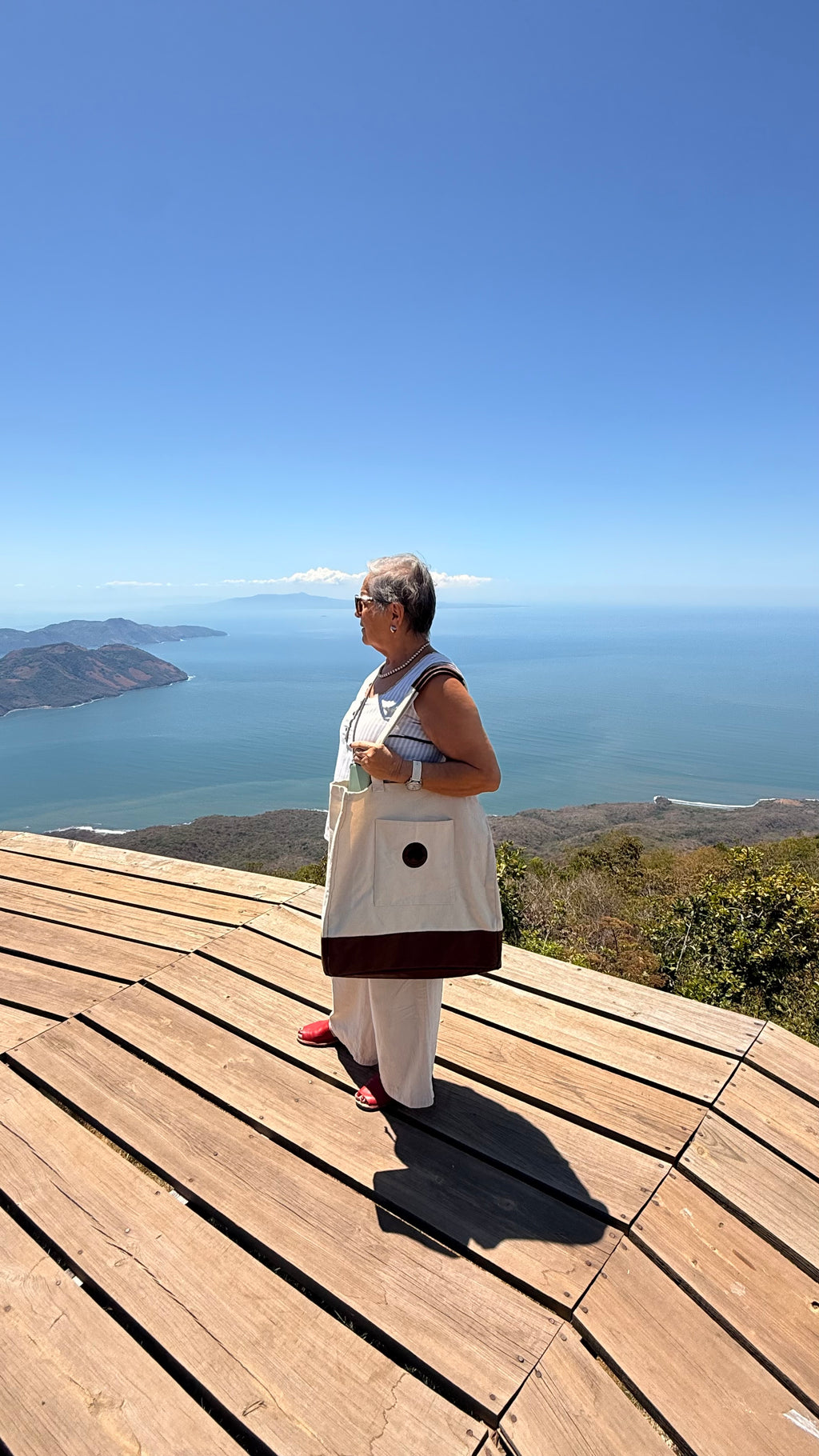 Woman carrying 503Cher@s Large Tote Bag on a hilltop overlook with ocean view in El Salvador