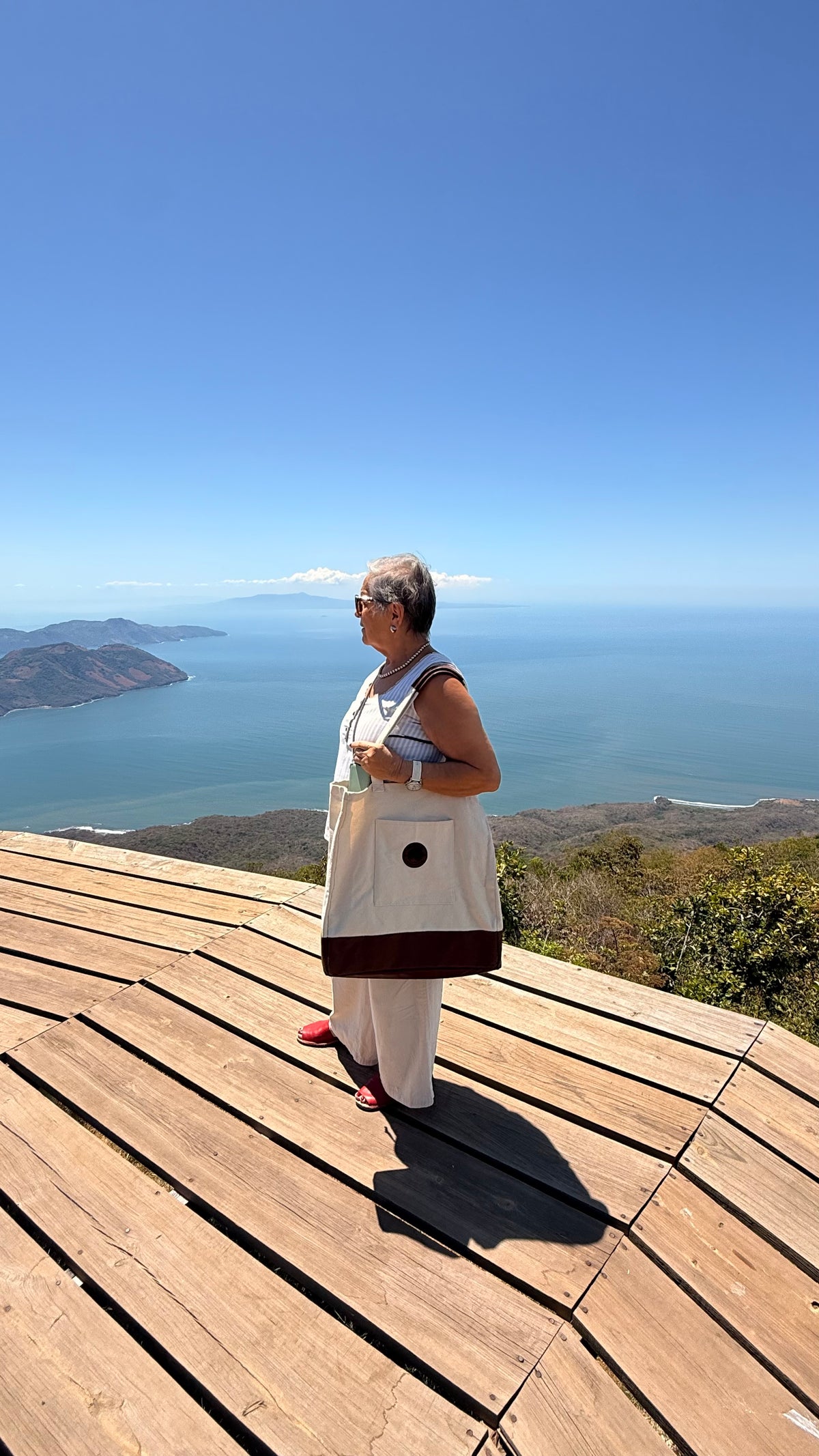 Woman carrying 503Cher@s Large Tote Bag on a hilltop overlook with ocean view in El Salvador